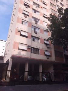 een hoog gebouw met ramen en een hek ervoor bij Apartamento para Temporada no Gonzaga in Santos