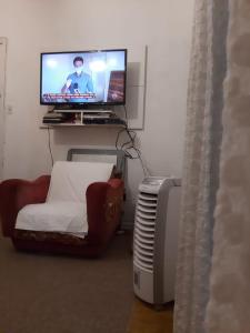een woonkamer met een flatscreen-tv en een stoel bij Apartamento para Temporada no Gonzaga in Santos