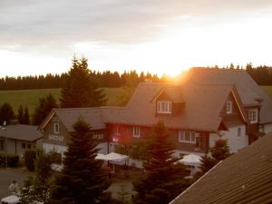 une maison au coucher du soleil derrière elle dans l'établissement Berggasthof zur Glocke, à Winterberg