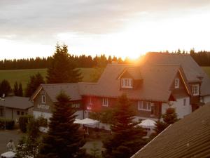 dom z zachodzącym słońcem za nim w obiekcie Berggasthof zur Glocke w mieście Winterberg