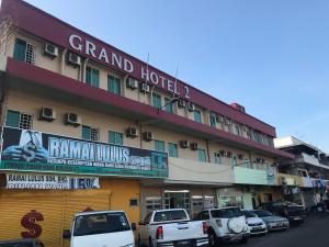 un grand hôtel avec des voitures garées devant lui dans l'établissement Grand Hotel 2, à Keningau