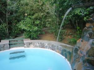 Manthally Cabanas في هيكادوا: حوض استحمام ساخن في حديقة مع شلال