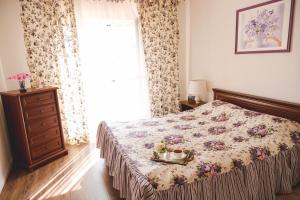 a bedroom with a bed with a floral bedspread and a window at Bonita in Zatoka