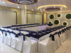 a banquet hall with a long table with white chairs at Hotel Sarvin in Lucknow