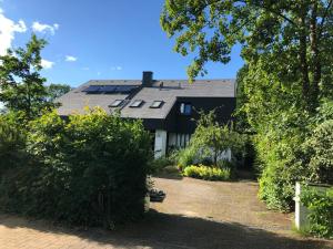 uma casa com um telhado preto e alguns arbustos em Seeblick em Fockbek