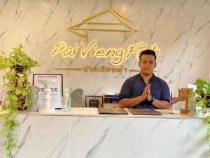 un hombre sentado en un mostrador en una habitación en Pai Vieng Fah Resort, en Pai
