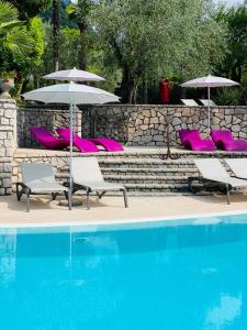 eine Gruppe von Stühlen und Sonnenschirmen neben einem Pool in der Unterkunft Villa Miravalle in Riva del Garda