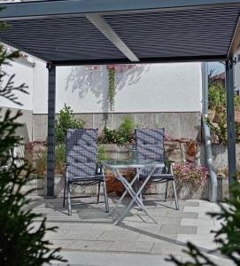 2 chaises et une table en verre sur la terrasse dans l'établissement Ferienapartment Schlosser, à Diez