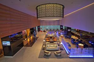 a large lobby with chairs and tables and a chandelier at Novotel Pune Viman Nagar Road in Pune