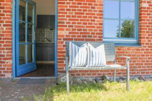 a bench with pillows sitting in front of a brick building at Ferienwohnungen Ostseestern in Rakow