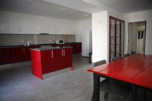 an empty kitchen with red cabinets and a red table at Casa da Praça - Ponte de Sor in Ponte de Sor