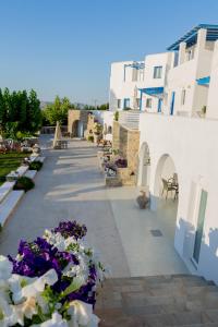 a courtyard with white buildings and purple and white flowers at Fragoulis Village in Parasporos