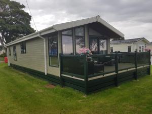 a house with a screened in porch on the grass at Sea views, fabulous modern lodge in Port Seton