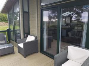 a screened in porch with two chairs and a table at Sea views, fabulous modern lodge in Port Seton