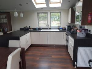 a kitchen with white cabinets and a black counter top at Sea views, fabulous modern lodge in Port Seton
