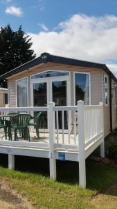 ein kleines Haus mit einer Veranda und einem Tisch in der Unterkunft Stunning modern lodge in Port Seton