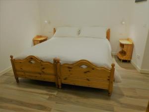 コマーノ・テルメにあるNido di Rondine B&Bのベッドルーム1室(白いシーツが備わる木製ベッド1台付)