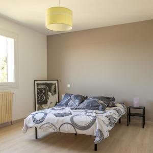 een slaapkamer met een bed in een witte kamer bij maison garrigue piscine hors sol pétanque in Pignan