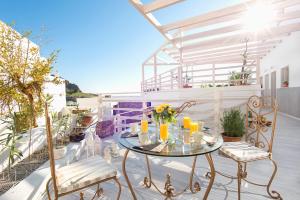 a patio with a glass table and chairs on a balcony at Lindos Harmony Suites in Lindos