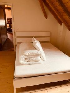 a bed with white sheets and pillows on it at Colonie 7 - Gastenkamers in Merksplas