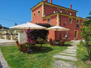 ein Haus mit Tischen und Sonnenschirmen davor in der Unterkunft Casa do Merlo in Barreiros