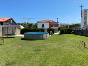 un gran patio con una cama elástica en el césped en Beach House with Swimming Pool, en Vila do Conde