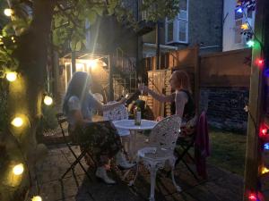 two women sitting at a table in a garden at night at Albert's Rest in Ramsgate +19 photos