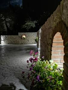 a stone wall with flowers and stairs at night at Nikoli Apartments in Benitses