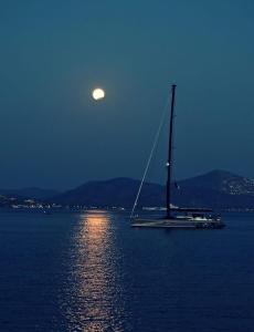 a sail boat in the water with the moon in the sky at Nikoli Apartments in Benitses