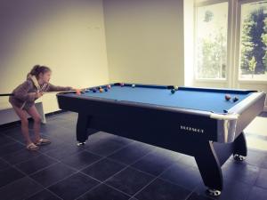 a woman playing pool in a room with a pool table at Vakantiewoning d'Hoppe in Flobecq