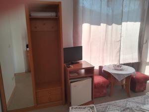 a small room with a desk and a tv and a table at Guest House Stenli in Primorsko