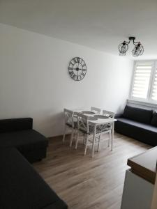 sala de estar con mesa, sillas y reloj en Apartament pod Szóstką, en Duszniki-Zdrój