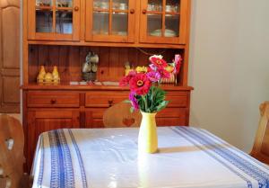 Żółta waza pełna kwiatów siedząca na stole w obiekcie Retro Vendégház w mieście Nagyharsány