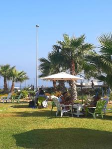 eine Gruppe von Menschen, die unter einem Schirm auf Gartenstühlen sitzen in der Unterkunft B&B Brezza Delle Egadi in Marsala