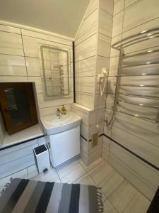a white bathroom with a sink and a mirror at Kozak's Dream in Kamianets-Podilskyi