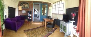 a living room with a purple couch and a blue door at Vrijstaand Koetshuis Marron in Barsingerhorn +13 photos