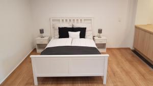 a white bed in a bedroom with two night stands at Ferienwohnung im Green in Bad Neuenahr-Ahrweiler