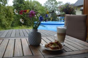 a table with a plate of food and a vase with flowers at Penzion pod Čeřinkem in Mirošov