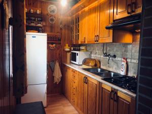 a kitchen with wooden cabinets and a white refrigerator at Zielona Sielanka in Orzyny