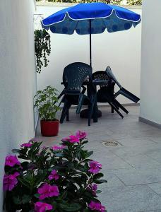 2 sillas y una sombrilla en un patio con flores en A Casa di Santé, en Arnesano