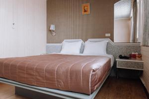 a bedroom with a large bed with two pillows at Tong Hsin Hotel in Pingtung City