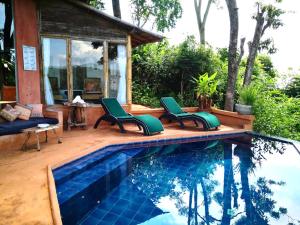 una piscina con 2 sillas verdes junto a una casa en Phu Chaisai Mountain Resort en Mae Salong Nai