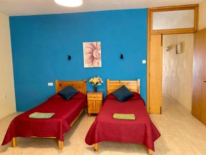 two beds in a room with blue walls at Gozo Belle Mare Apartments in Marsalforn