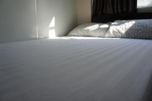 um quarto com uma cama com uma colcha branca em Ocean Inn em Hong Kong