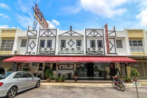 a car parked in front of a building with a red awning at Rose Cottage Hotel Taman Daya in Johor Bahru