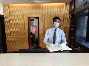 a man in a mask sitting at a table with a book at Hotel Avon International in Aurangabad