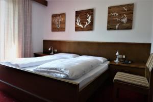 a bedroom with a bed with white sheets and antlers on the wall at Pension Dolomieu in Santa Cristina Gherdëina