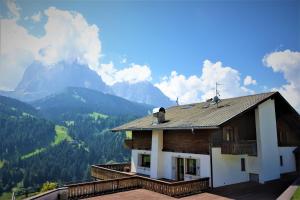 una casa en un balcón con montañas en el fondo en Pension Dolomieu, en Santa Cristina Valgardena