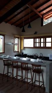 a kitchen with a large island with chairs around it at Pousada Recanto da Serra in São Pedro da Serra