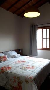 um quarto com uma cama com colcha floral e uma janela em Pousada Recanto da Serra em São Pedro da Serra